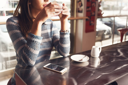 Pensive young woman at the bar having a cup of coffeeの写真素材