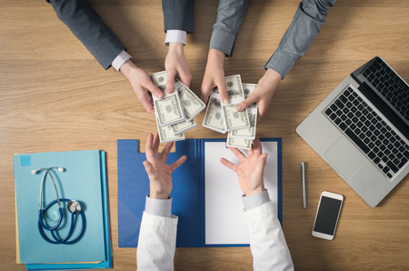 Male patient having a medical visit and bribing a greedy doctor with a lot of money top view unrecognizable peopleの写真素材