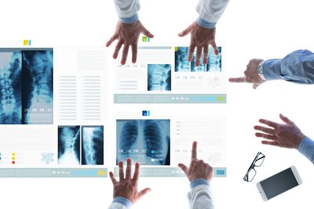 Professional medical team examining patient's medical records and x-ray on touch screen slides and pointingの写真素材