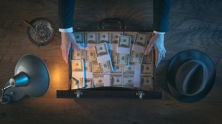 Vintage rich businessman's desk holding a briefcase filled with dollar packs, top viewの写真素材