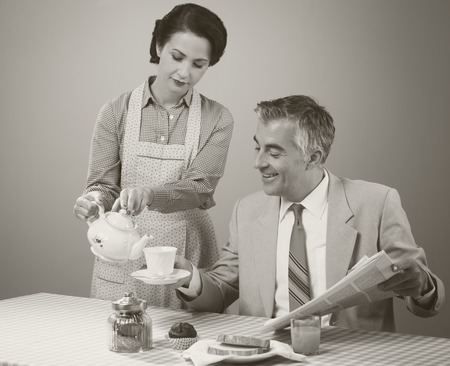 1950s beautiful woman serving tea for breakfast to her smiling husbandの写真素材