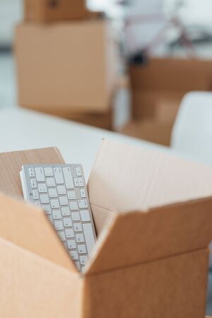 Open cardboard box and empty office on background, relocation concept, selective focus