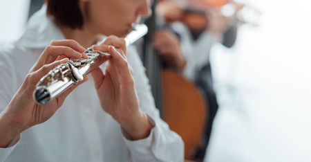 Professional female flute player performing with classical music symphony orchestra, unrecognizable personの写真素材