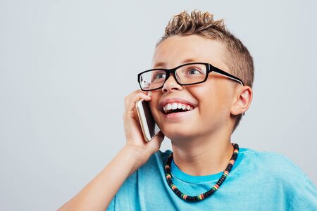 Smiling young boy having a phone call with his touch screen smart phoneの写真素材
