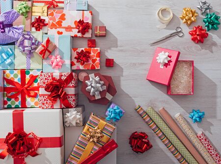 Gift boxes wrapping on a desk with paper rolls, ribbons and scissors, celebrations and Christmas conceptの写真素材