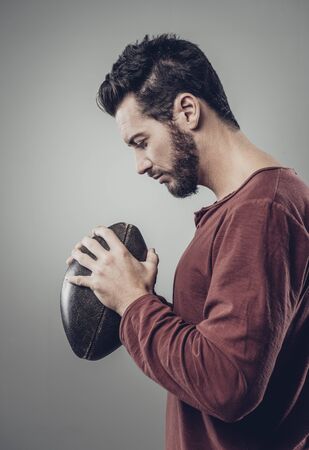 Young attractive football player with ball on gray backgroundの写真素材
