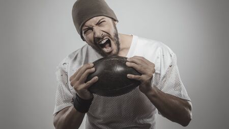 Handsome muscular football player holding ball and posingの写真素材