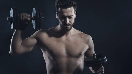 Male attractive body builder working out with dumbbells, strength and fitness conceptの写真素材