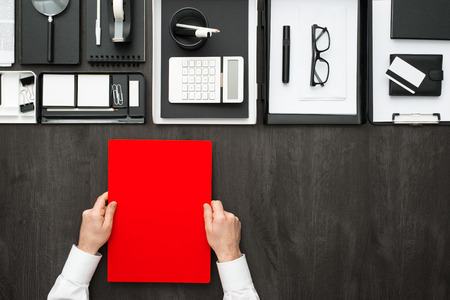 Corporate businessman working at office desk, he is holding a folder, business and finance concept, flat layの写真素材