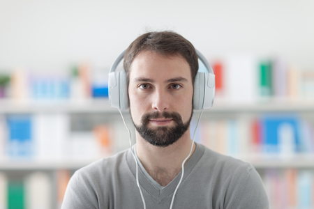 Young handsome man listening to music using headphones, enjoyment and leisure conceptの写真素材