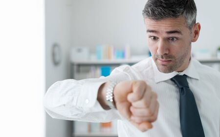 Stressed anxious businessman in a hurry checking time, he is late for his business appointmentの写真素材