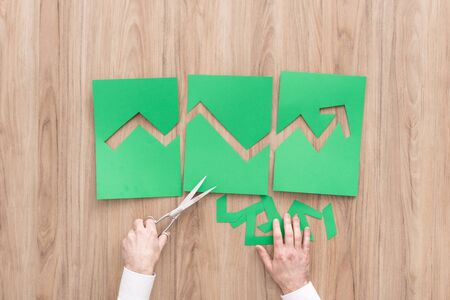 Businessman composing a successful financial graph with arrow going up, he is using scissors and paper cuts, successful green business conceptの写真素材
