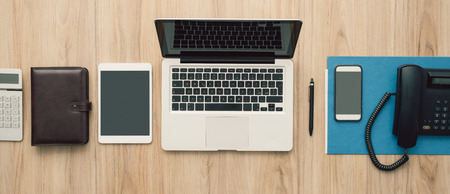 Flat lay business office desktop with laptop, tablet, smartphone and telephone