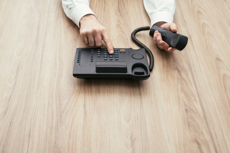 Businessman dialing a number and calling with a telephone, communication and business consulting conceptの写真素材