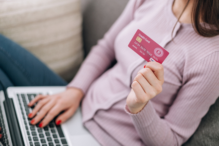 Woman relaxing on the sofa at home and shopping online using a credit cardの写真素材