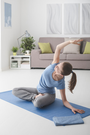 Young woman at home practicing yoga on the floor, healthy lifestyle and fitness conceptの写真素材