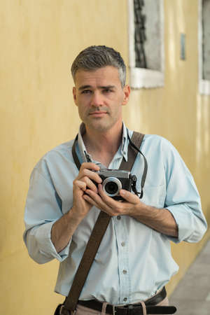 Confident photographer exploring a city and taking pictures with a digital cameraの写真素材