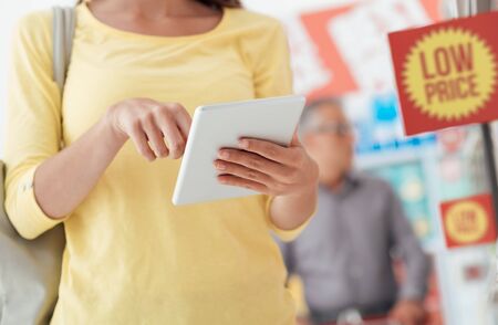 Woman doing grocery shopping and using apps on her digital tablet, technology and merchandising conceptの写真素材