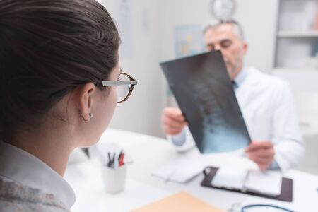 Professional doctor and radiologist giving a consultation to his patient, he is examining and x-ray...
