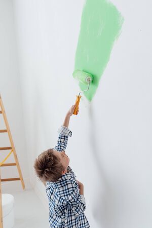 Happy cute boy painting a house wall using a paint roller, home renovation conceptの写真素材