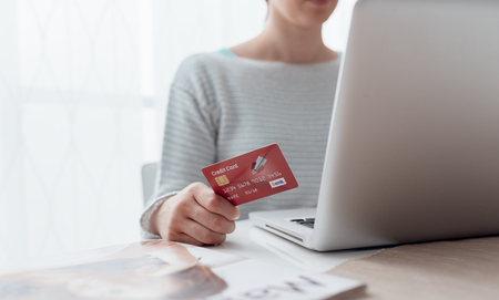 Woman connecting with a laptop and doing online shopping using a credit cardの写真素材