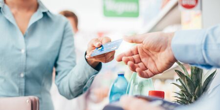 Woman at the supermarket checkout, she is paying using a credit card, shopping and retail conceptの写真素材