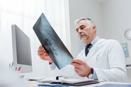 Professional doctor and radiologist giving a consultation to his patient, he is examining and x-ray...