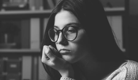 Sad young woman posing with hand on chin, she is depressed and pensiveの写真素材
