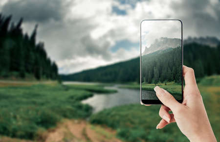 Tourist taking a picture of Dolomites and nature scenics using a smartphone, point of view shotの写真素材