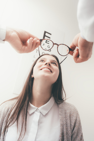 Young happy woman trying her new pair of glasses after the eye examの写真素材