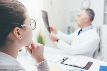 Professional doctor and radiologist giving a consultation to his patient, he is examining and x-ray imageの写真素材