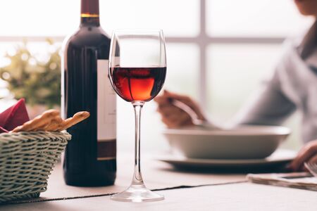 Woman having lunch at the restaurant and drinking a glass of red wine, fine dining and wine tasting conceptの写真素材