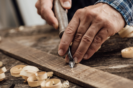 Professional carpenter at work, he is carving wood using a woodworking tool, hands close up, carpentry and craftsmanship conceptの写真素材