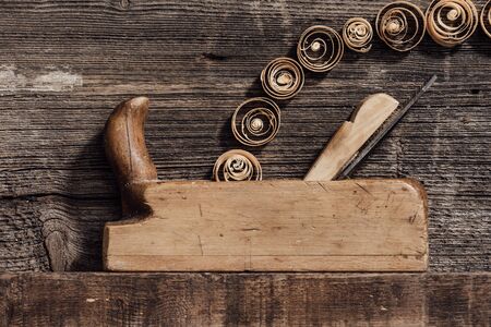 Old wood planer smoothing a wood block and spiral shavings: carpentry, woodworking and craftsmanship conceptの写真素材