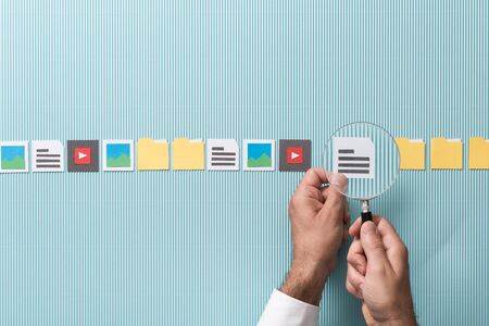 File search, scan and analysis: man zooming in on a file using a magnifier, paper cut iconsの写真素材