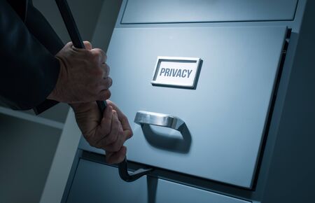 Burglar opening a drawer in the office at night using a crowbar, he is stealing confidential data...