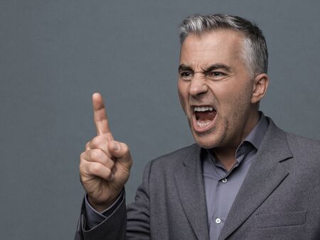 Aggressive angry boss giving a reprimand and arguing, he is pointing with his finger and yellingの写真素材