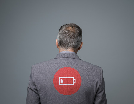 Tired businessman with low charge icon, stress and fatigue concept, back viewの写真素材