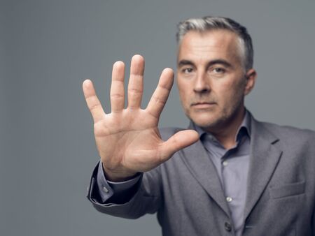 Businessman doing a stop gesture with his hand, rejection and denial conceptの写真素材