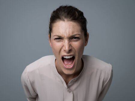 Aggressive angry woman yelling at camera, stress and negative feelings concept