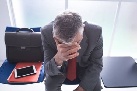 Depressed stressed businessman sitting in the waiting room and waiting for a job interview, unemployment and business failure conceptの写真素材