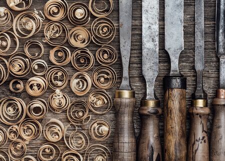 Set of used professional carving tools on the workbench and wood shavings close up: carpentry, craftsmanship and handwork conceptの写真素材