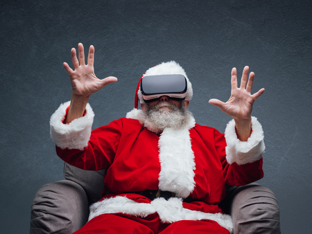 Santa Claus experiencing virtual reality, he is wearing VR glasses and interacting with a virtual environmentの写真素材