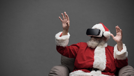 Santa Claus experiencing virtual reality, he is wearing VR glasses and interacting with a virtual...