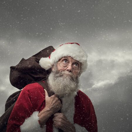 Happy Santa Claus carrying an heavy sack with Christmas giftsの写真素材