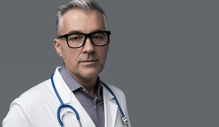 Confident chief physician posing on gray background, medicine and healthcare professionals concept