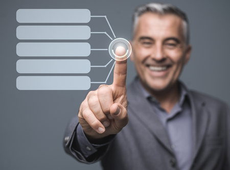 Confident businessman using a virtual touch screen interface and selecting items on a chart, business and futuristic technologies conceptの写真素材