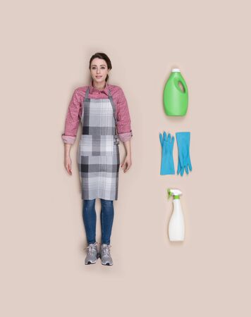 Lifelike smiling housewife human doll with apron and housekeeping objects, flat layの写真素材