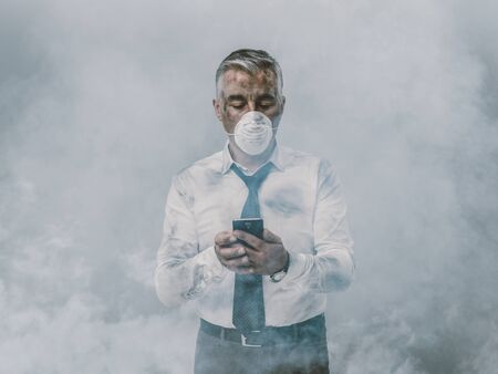 Corporate business executive with protective mask and polluted air, he is using a smartphone