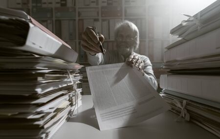 Senior office worker showing a contract and asking for a signature, bureaucracy and agreements conceptの写真素材